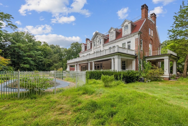 rear view of property with a balcony, a garage, and a yard