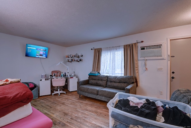 living room featuring a textured ceiling, wood-type flooring, and a wall mounted air conditioner