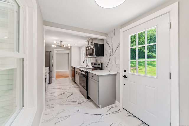 kitchen with sink, a chandelier, gray cabinets, appliances with stainless steel finishes, and decorative backsplash