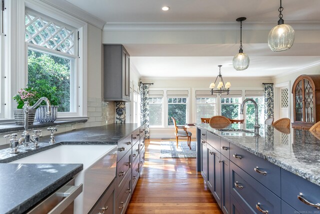 kitchen featuring dark stone countertops, a wealth of natural light, light hardwood / wood-style floors, and sink