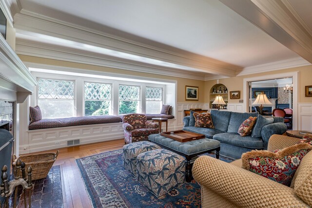 living room with hardwood / wood-style flooring, a fireplace, beam ceiling, and crown molding