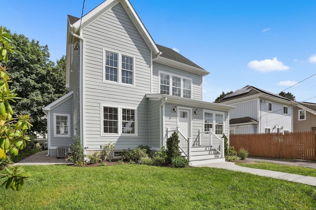 view of front of property with fence, central AC, and a front yard