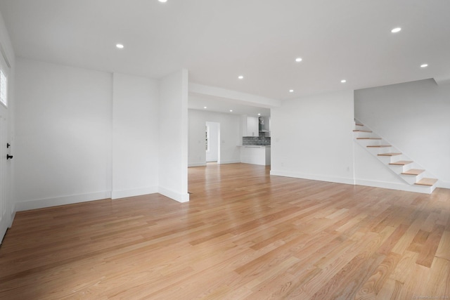 unfurnished living room with light wood-type flooring, stairs, baseboards, and recessed lighting