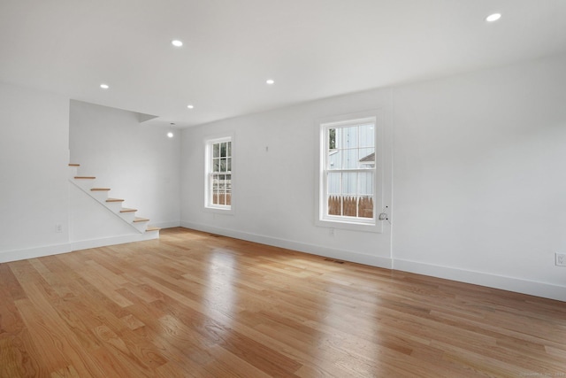 unfurnished room featuring stairway, plenty of natural light, and light wood-style flooring