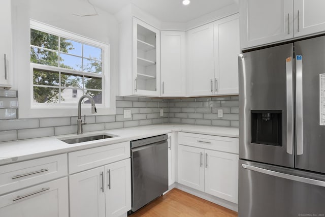 kitchen with decorative backsplash, appliances with stainless steel finishes, glass insert cabinets, white cabinets, and a sink