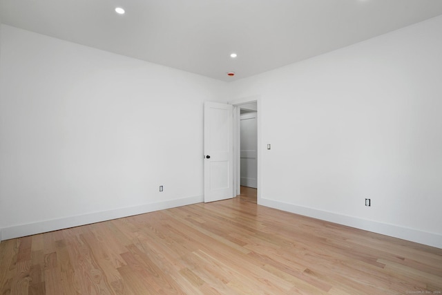 spare room featuring light wood finished floors, baseboards, and recessed lighting