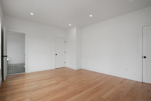 spare room with light wood finished floors, recessed lighting, and baseboards