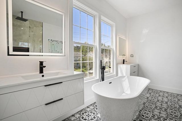 full bath with a soaking tub, a stall shower, vanity, baseboards, and tile patterned floors