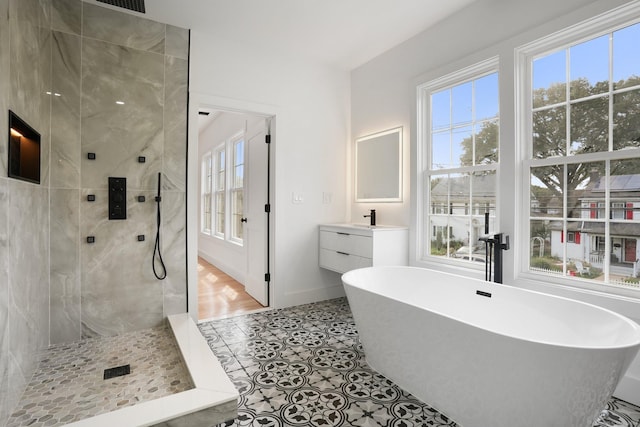 bathroom with a freestanding tub, vanity, baseboards, tile patterned floors, and walk in shower