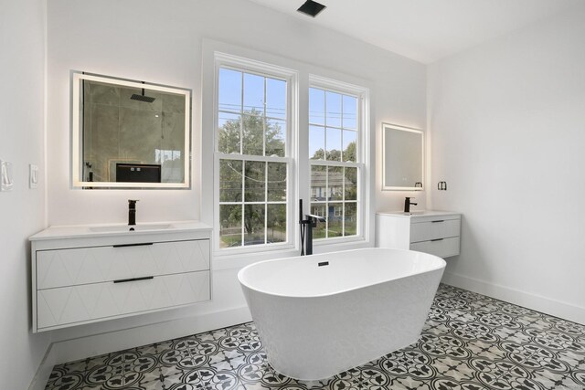 full bath with a freestanding tub, tile patterned flooring, two vanities, and a sink