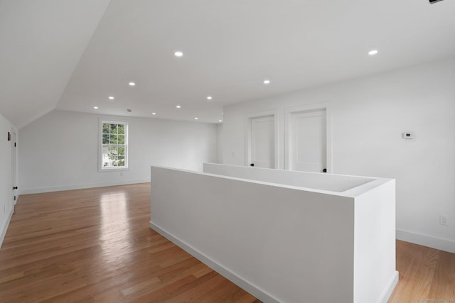 interior space featuring lofted ceiling, light wood-style flooring, baseboards, and recessed lighting