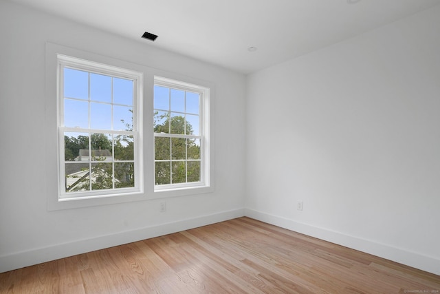 empty room with baseboards, light wood-style flooring, and a healthy amount of sunlight