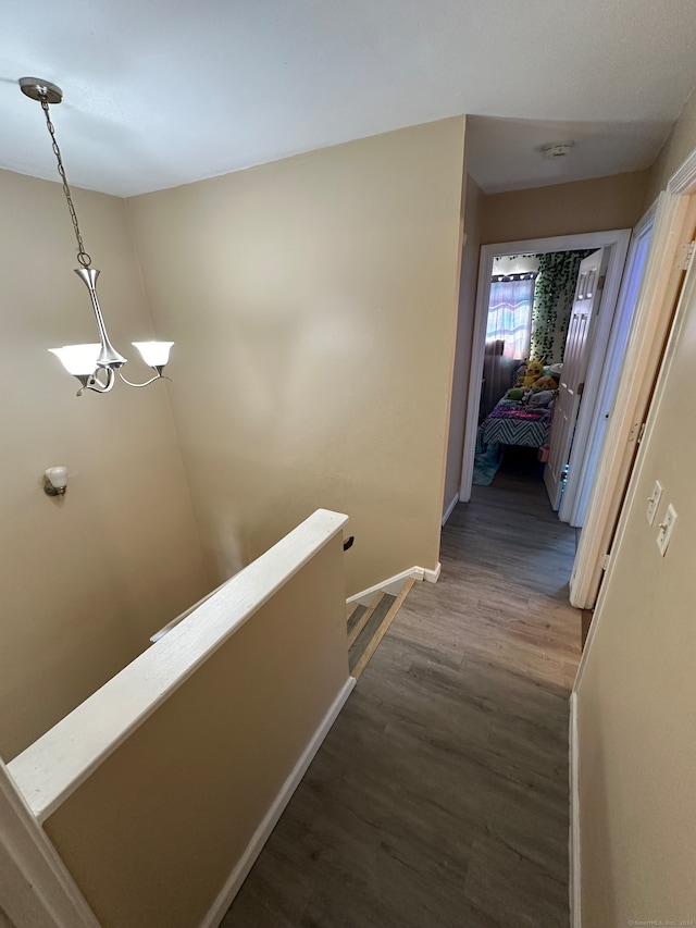 hallway with an inviting chandelier and hardwood / wood-style floors