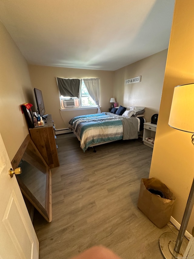 bedroom featuring hardwood / wood-style flooring, cooling unit, and a baseboard heating unit