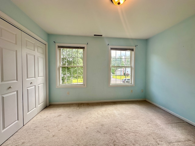 unfurnished bedroom featuring a closet and light carpet