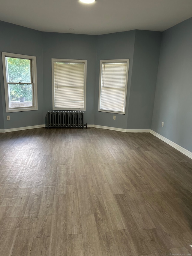 unfurnished room with hardwood / wood-style flooring and radiator heating unit