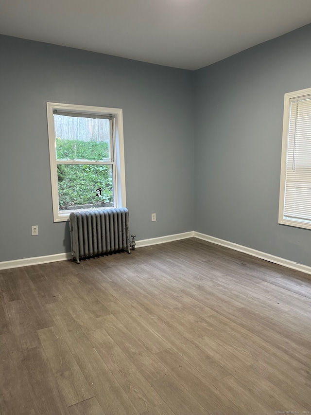 spare room with radiator heating unit and light wood-type flooring