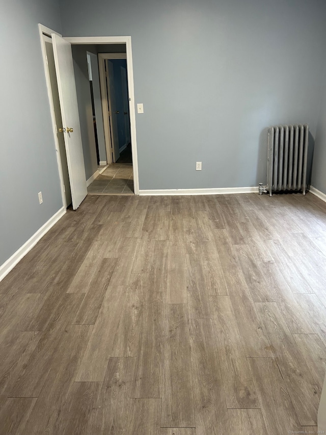 empty room with wood-type flooring and radiator