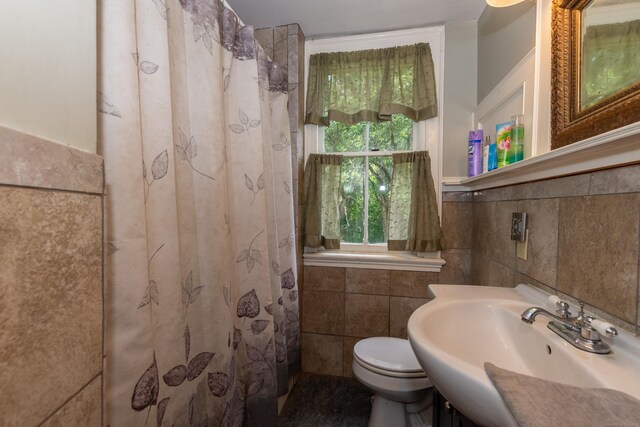 bathroom featuring decorative backsplash, a shower with shower curtain, toilet, tile walls, and sink