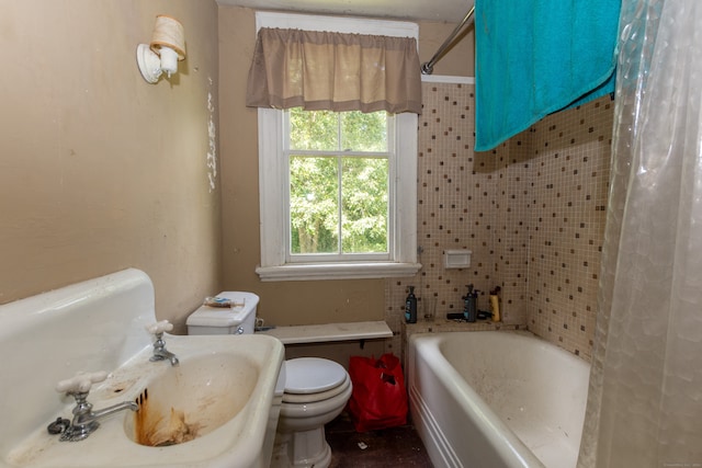 bathroom featuring toilet, a healthy amount of sunlight, and shower / tub combo