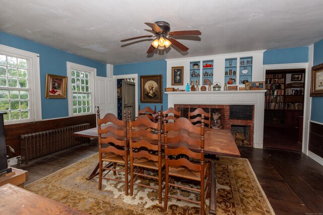 dining space with ceiling fan, a fireplace, hardwood / wood-style floors, and radiator