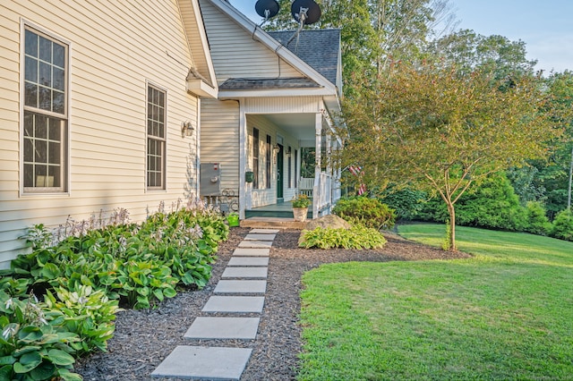 doorway to property featuring covered porch and a yard