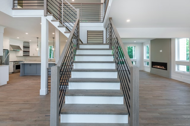 staircase with hardwood / wood-style floors, plenty of natural light, and a towering ceiling