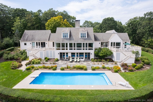 rear view of house featuring a patio area, a pool side deck, and a lawn