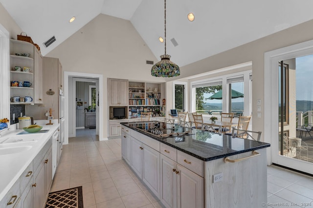 kitchen featuring a kitchen island, black electric stovetop, high vaulted ceiling, and light tile patterned flooring