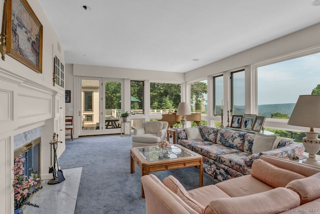 carpeted living room with a water view, a wealth of natural light, and a fireplace