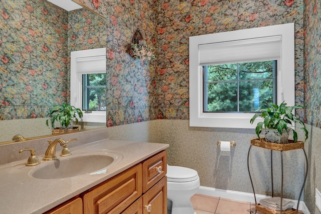 bathroom featuring vanity, toilet, a healthy amount of sunlight, and tile patterned floors