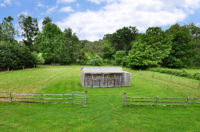 view of yard featuring an outbuilding, a rural view, and fence