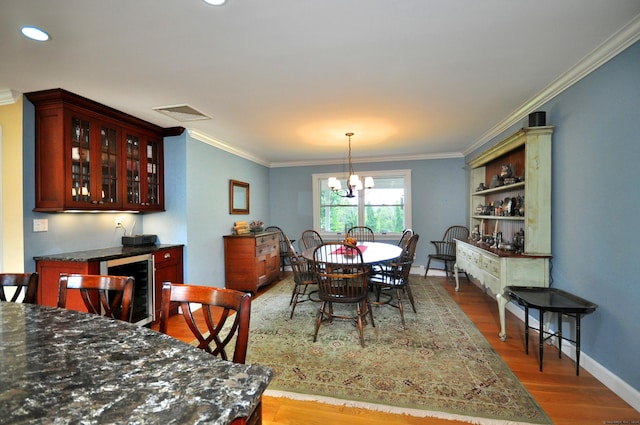 dining space featuring ornamental molding, wine cooler, baseboards, and wood finished floors