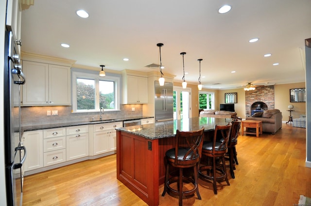 kitchen with decorative backsplash, light wood-style flooring, appliances with stainless steel finishes, a center island, and a sink