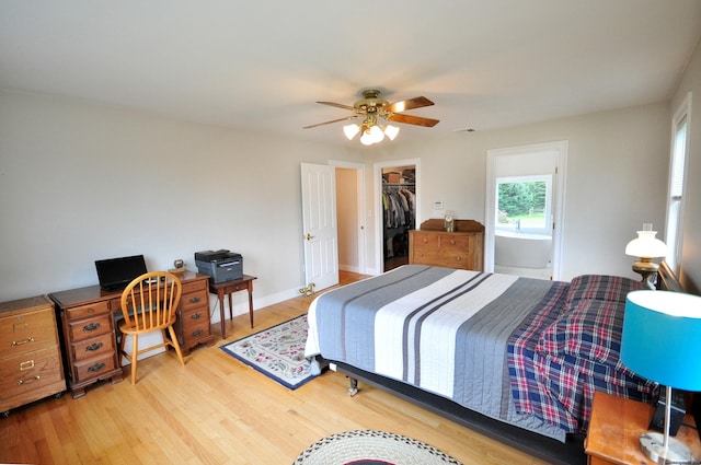 bedroom featuring light wood finished floors, a closet, visible vents, a spacious closet, and a ceiling fan