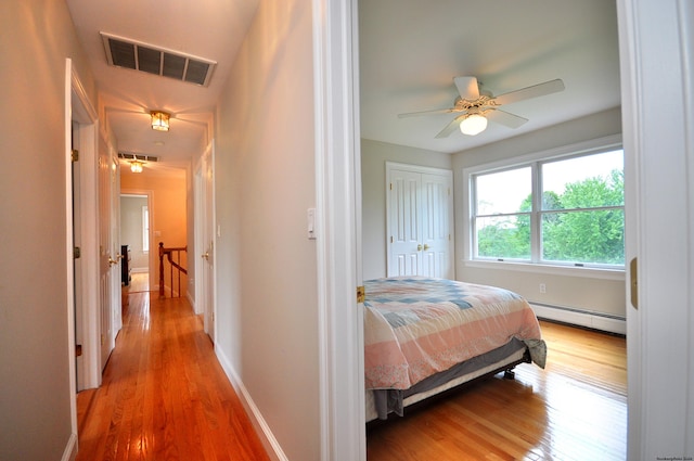 bedroom with visible vents, baseboards, a baseboard radiator, ceiling fan, and light wood-style floors