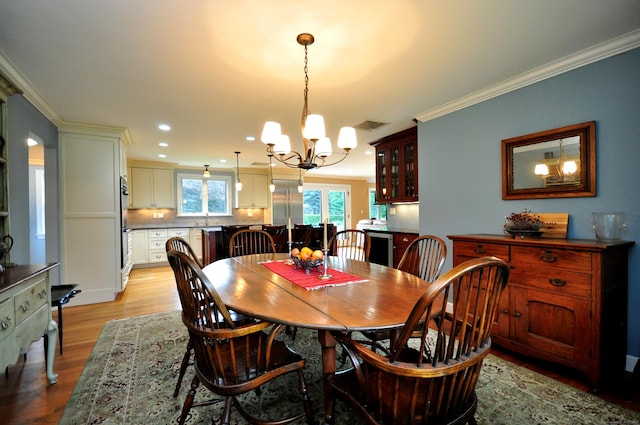 dining space featuring light wood-style floors, recessed lighting, ornamental molding, and an inviting chandelier