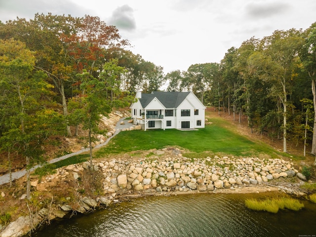 back of property featuring a lawn and a water view