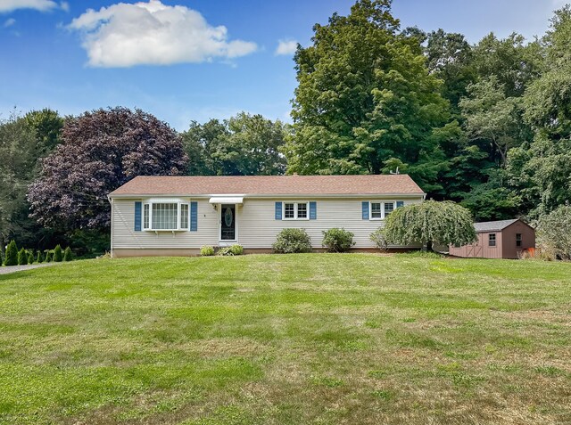 single story home featuring a storage shed and a front yard