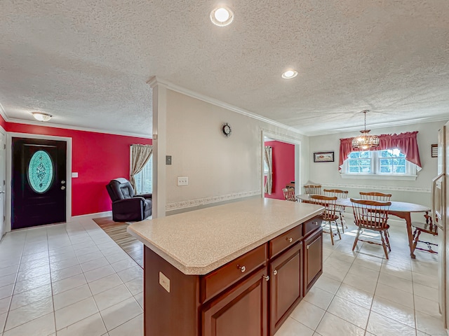 kitchen with decorative light fixtures, a center island, crown molding, and a textured ceiling