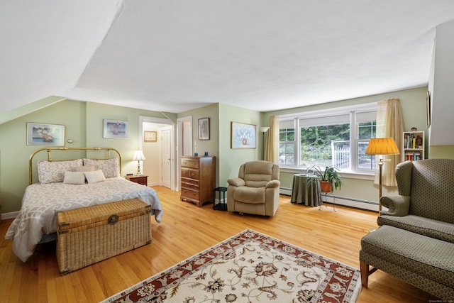 bedroom featuring a baseboard heating unit, hardwood / wood-style floors, and vaulted ceiling