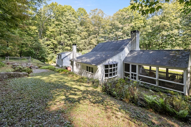 rear view of property with a sunroom and a lawn