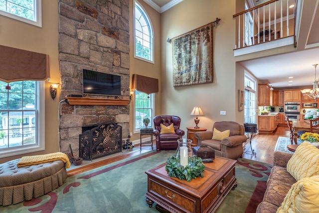 living room featuring a wealth of natural light, crown molding, hardwood / wood-style flooring, and a towering ceiling