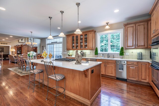 kitchen featuring dark hardwood / wood-style floors, hanging light fixtures, a breakfast bar, a center island, and tasteful backsplash