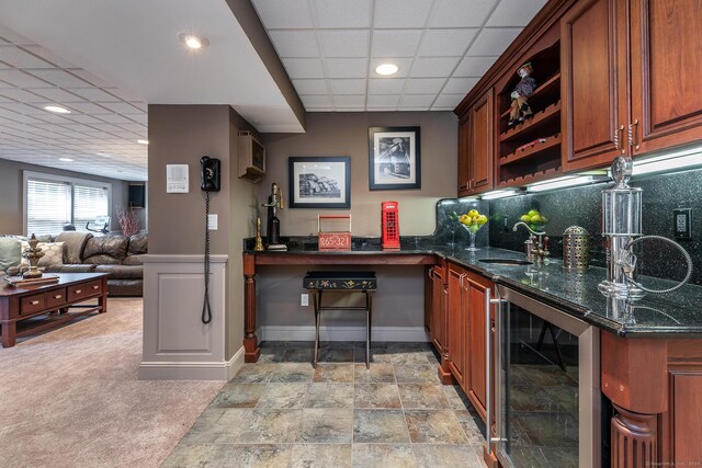 bar with sink, a drop ceiling, light carpet, dark stone counters, and wine cooler