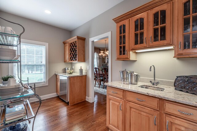 kitchen with dark wood-type flooring, sink, an inviting chandelier, stainless steel dishwasher, and light stone counters