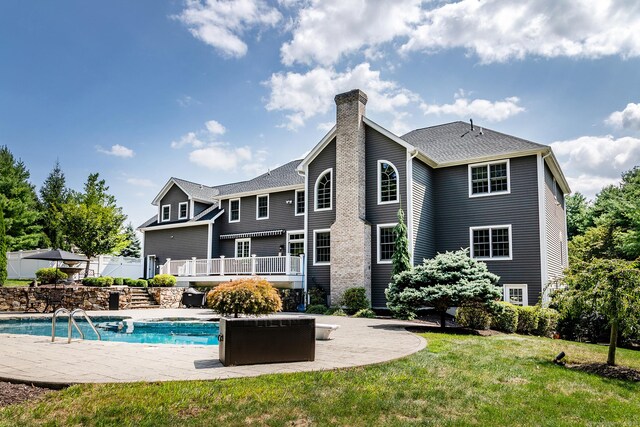 back of house featuring a lawn and a swimming pool side deck