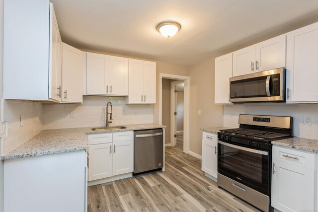 kitchen with white cabinetry, appliances with stainless steel finishes, sink, and light hardwood / wood-style flooring