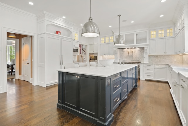 29 Sturges Commons, Westport, CT 06880 - kitchen featuring dark wood-style floors, a kitchen island with sink, decorative backsplash, white cabinetry, and appliances with stainless steel finishes