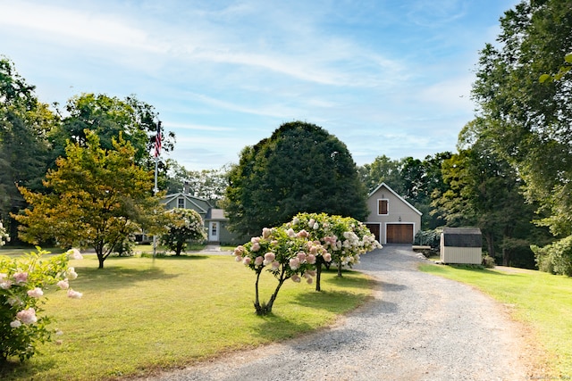 view of front facade featuring a storage unit, a garage, and a front lawn